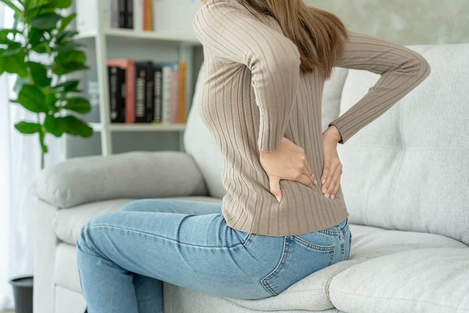 Woman experiencing persistent lower back pain, possibly linked to ankylosing spondylitis.