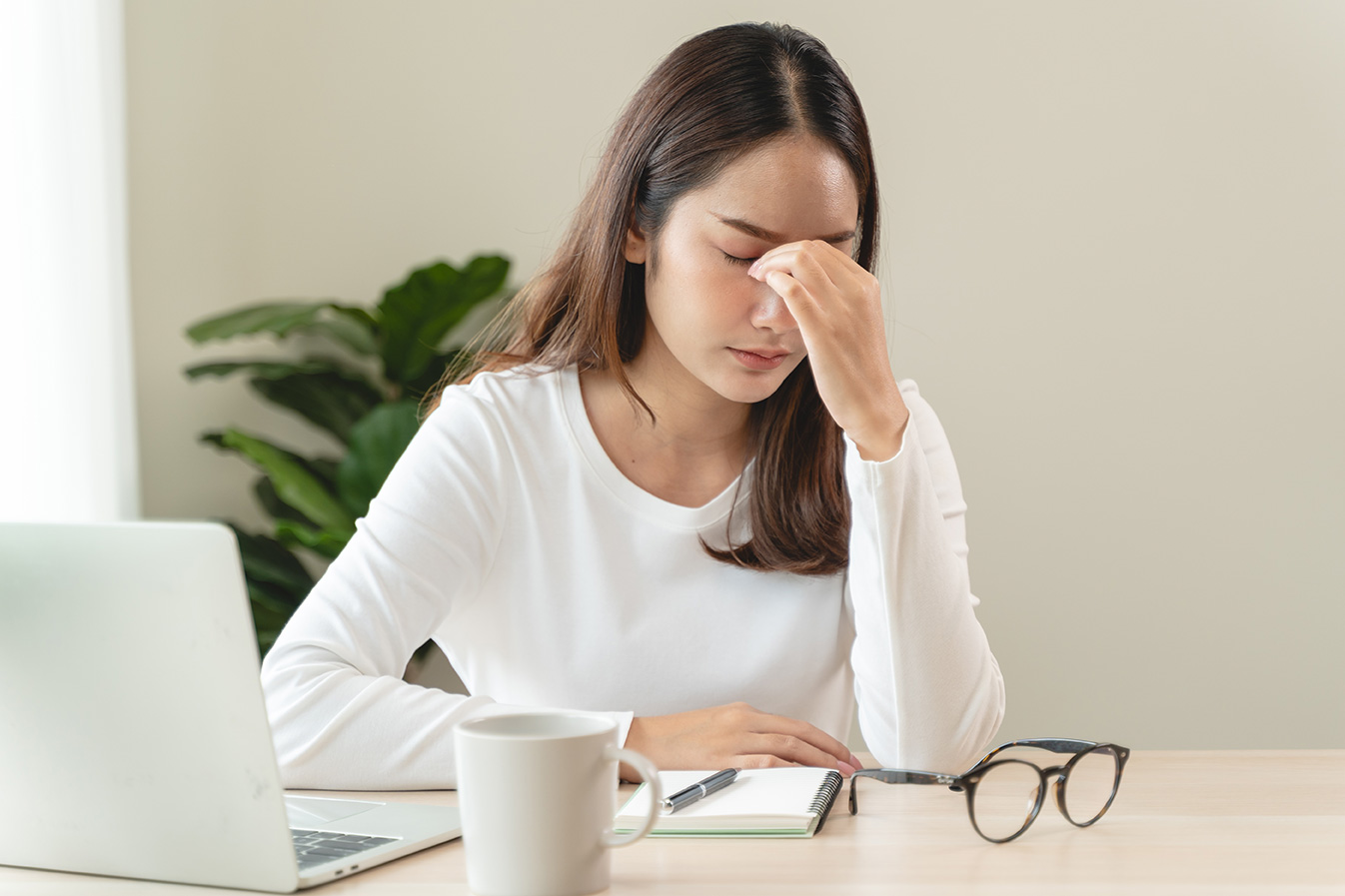 Woman appearing fatigued, sitting at desk with low energy and a tired expression. 