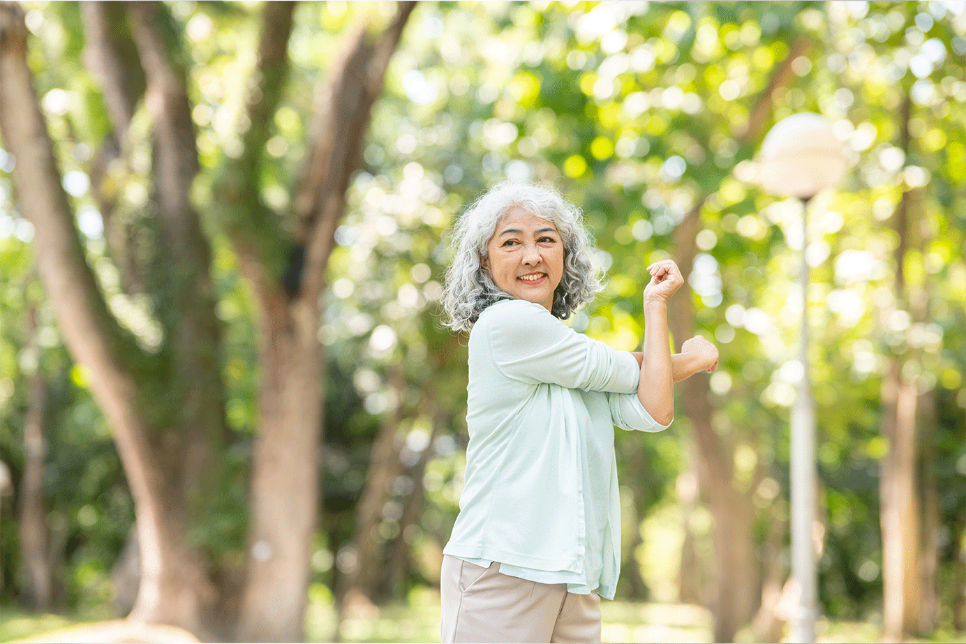 Elderly Asian woman stretching outdoors, promoting an active and healthy lifestyle.