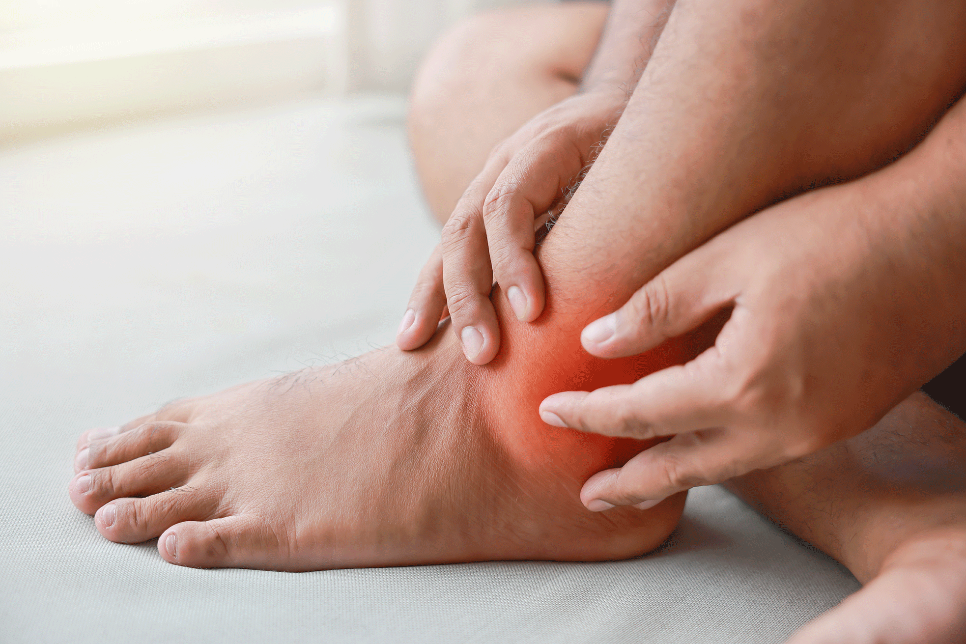 Man with swollen and red ankle joint, illustrating inflammation that can occur with gout flares.