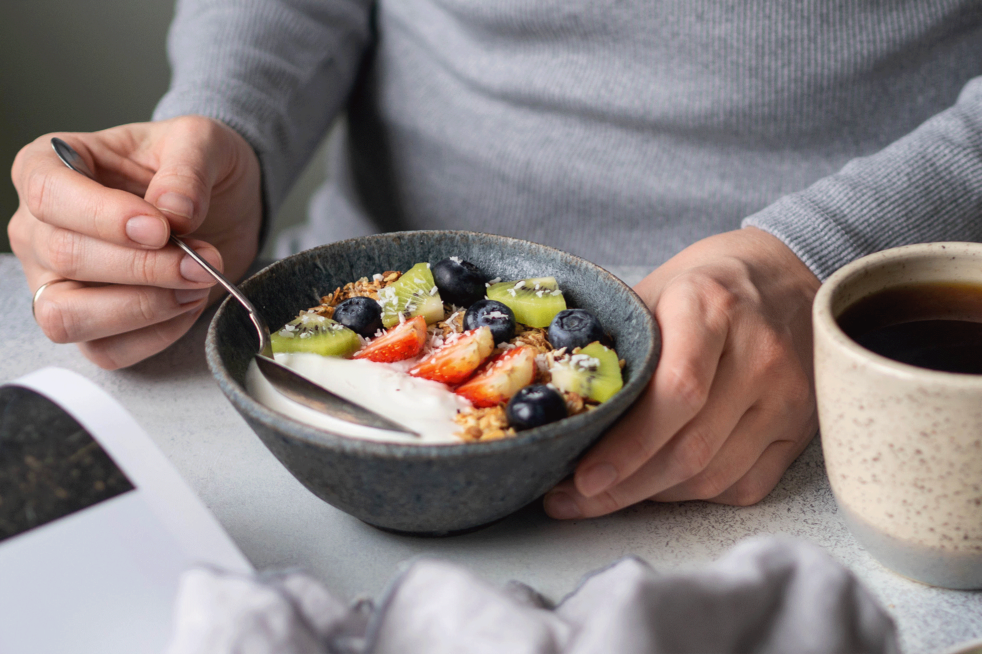 Woman at a breakfast table with healthy food options suitable for a gout‑friendly diet.