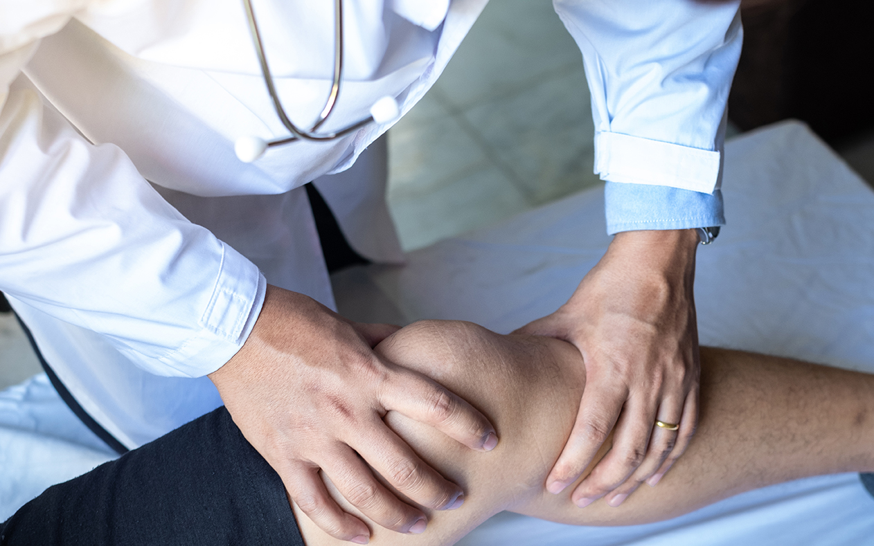 Doctor examining a patient's knee during a rheumatoid arthritis assessment.