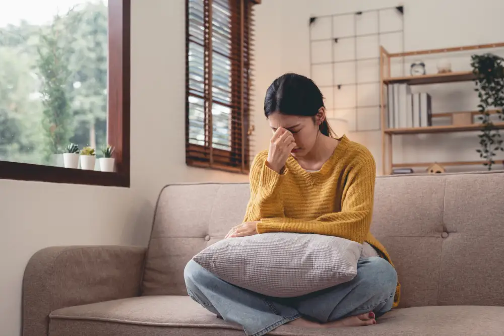 Woman sitting on a sofa looking fatigued and lacking energy.