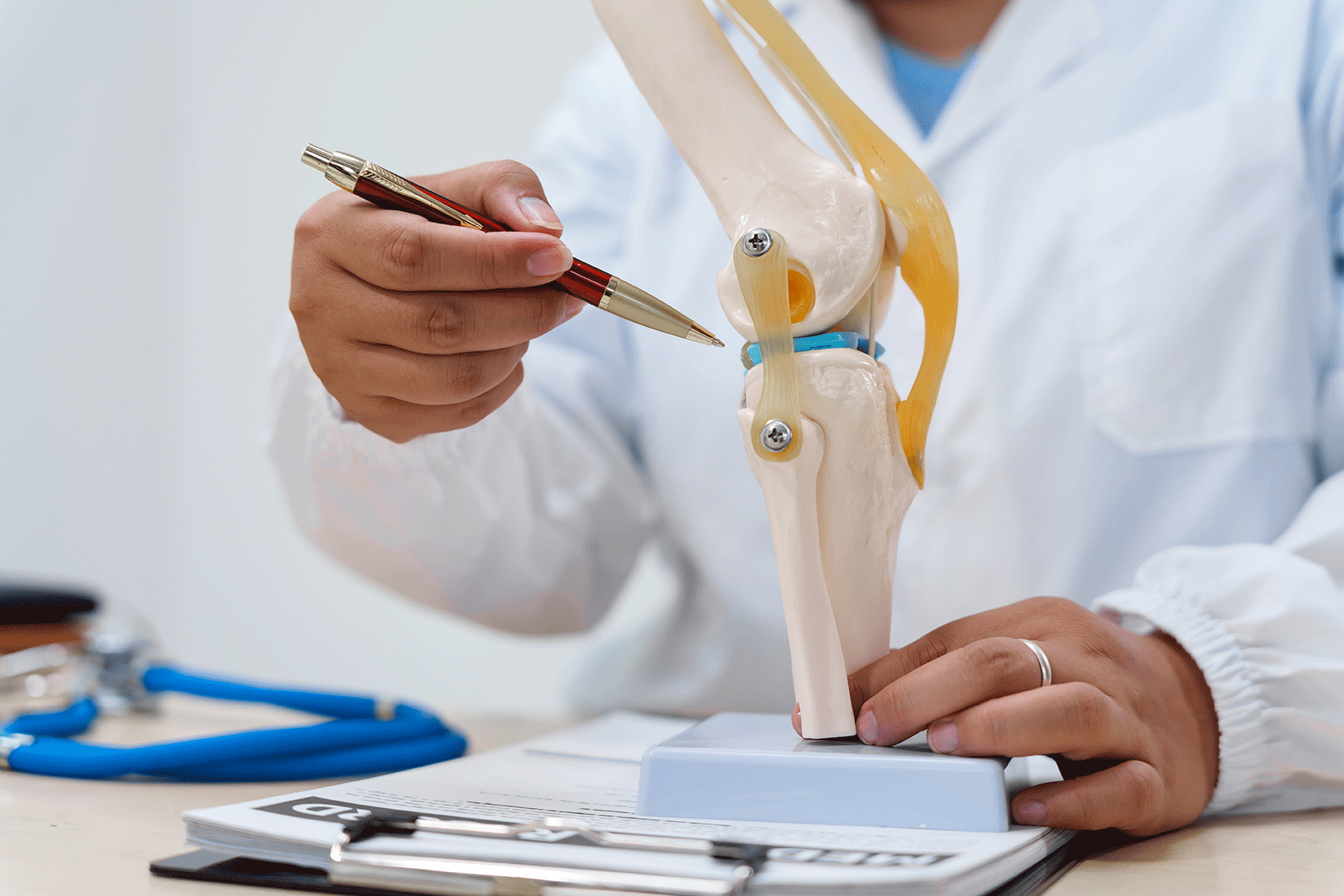 Doctor reviewing a knee X‑ray on a tablet during an assessment of arthritis in the knee joint.