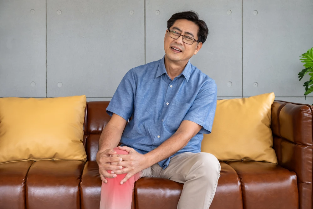 Man holding his knee during a gout flare, showing discomfort in the affected joint. 