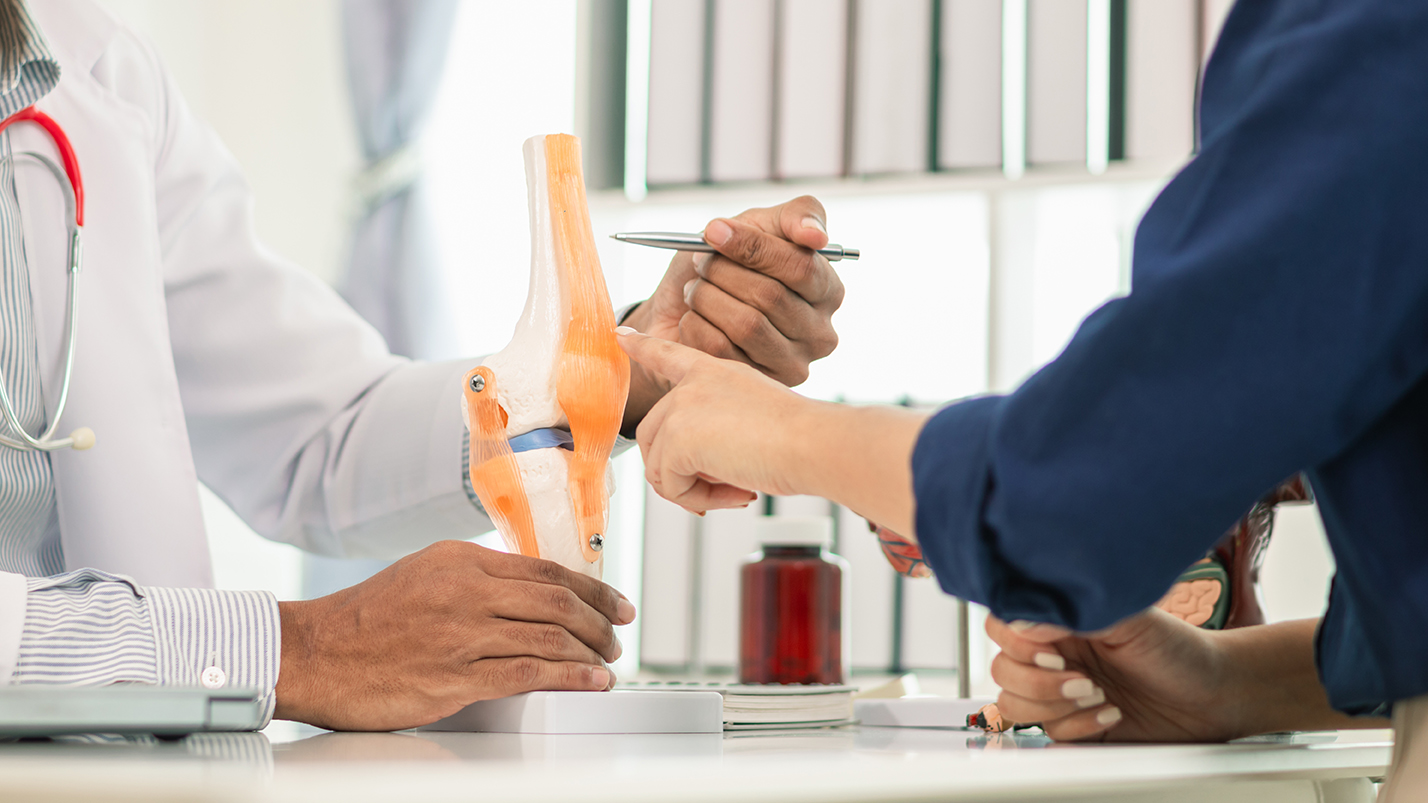 Man consulting a doctor in a clinic for rheumatism-related knee pain.