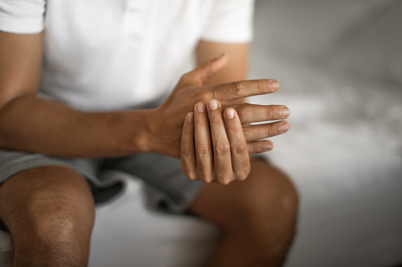 Man experiencing arthritis-related joint pain and stiffness in the fingers. 