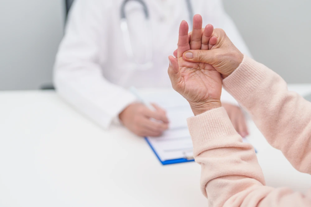 Woman experiencing gout pain in her fingers during a consultation with a gout doctor.